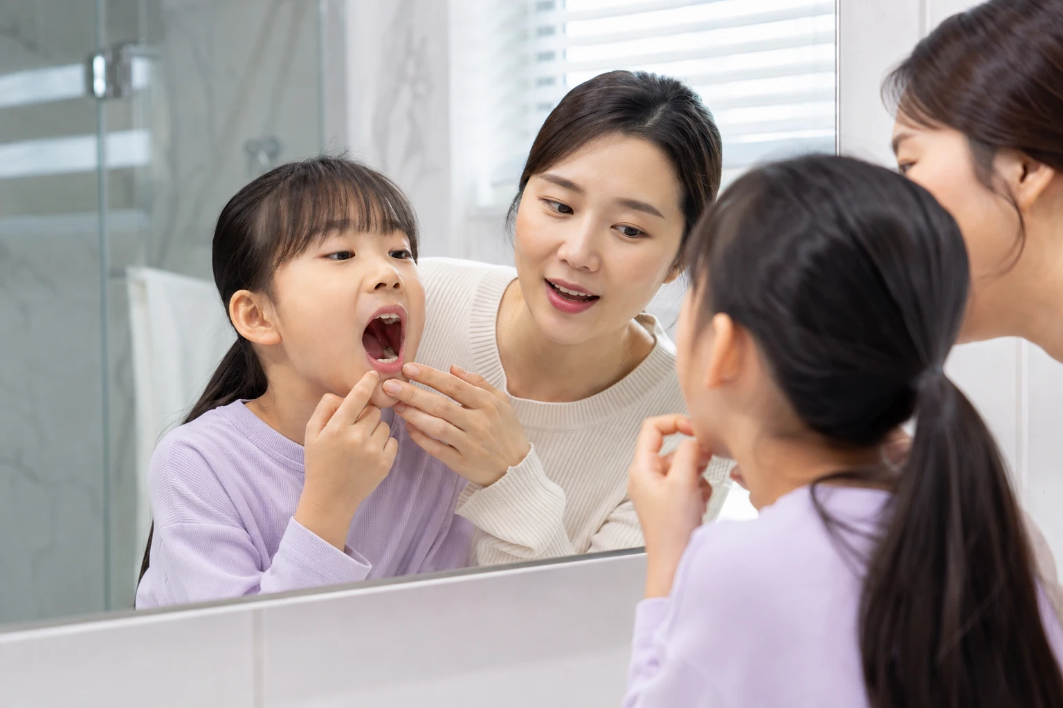 어금니 영구치가 나는 시기를 확인하는 보호자와 아이